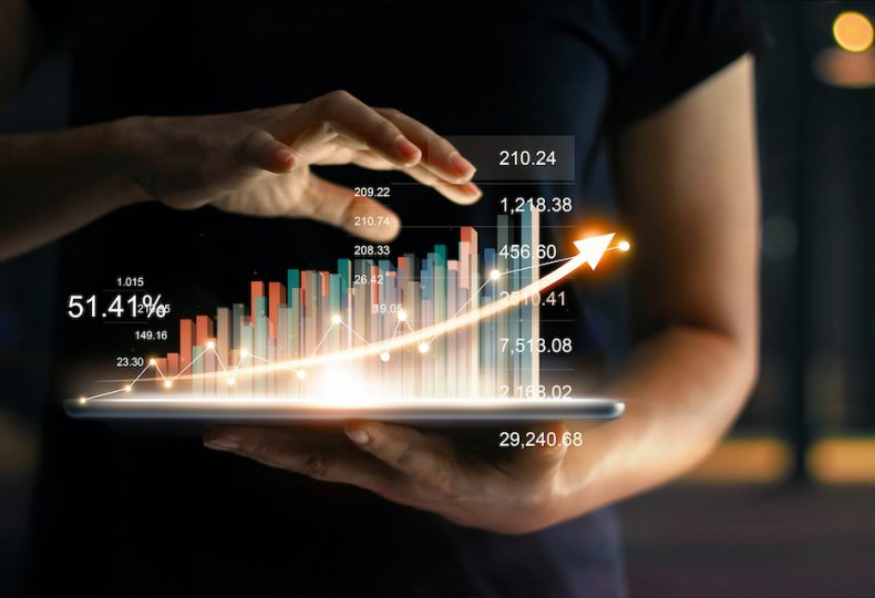 businessman holding tablet and showing a growing virtual hologram of statistics, graph and chart with arrow up on dark background. Stock market. Business growth, planing and strategy concept.