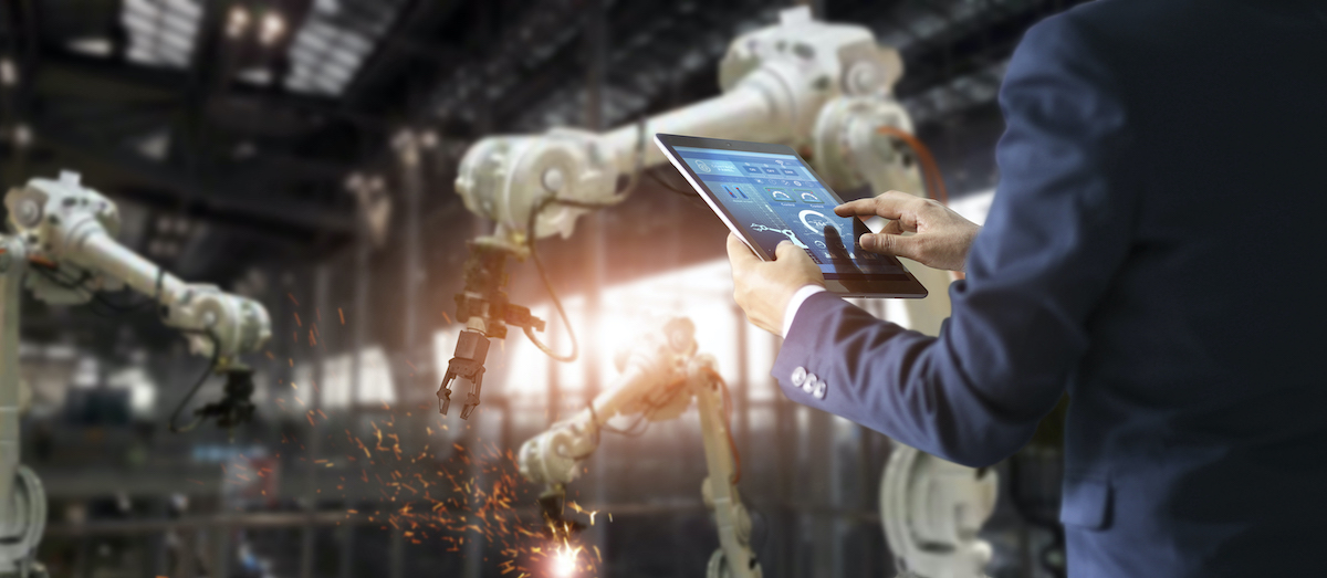 Manager industrial engineer using tablet check and control automation robot arms machine in intelligent factory industrial on real time monitoring system software. Welding roboticts and digital manufacturing operation. Industry 4.0 concept